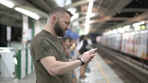 Man standing on the train station and browsing internet on smartphone Stock Footage 88538935