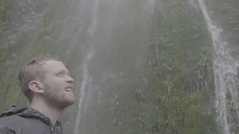 Man standing under the cascade falling from Canadian Rockies Stock Footage 69740542