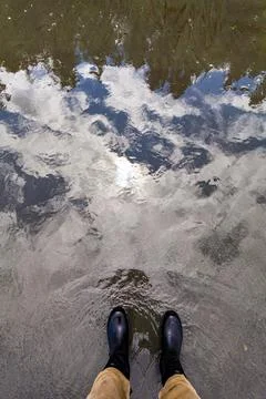 A man standing at the water's edge, a reflection of the forest and the sky .. Stock Photos
