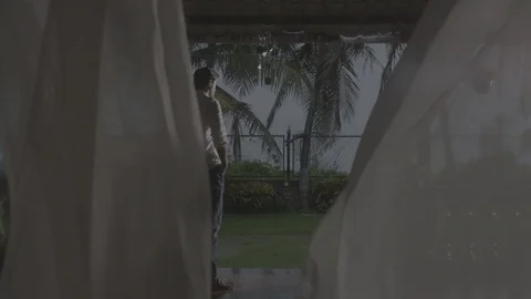 Man standing while it's raining outside with the flying curtains Stock-Footage 90611469