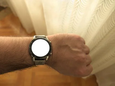 A man standing by a window and looking at a smart watch on his wrist POV Stock Photos