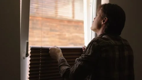 Man standing at the window and opening curtains silhouette of a man in the dark Stock Footage 306321447