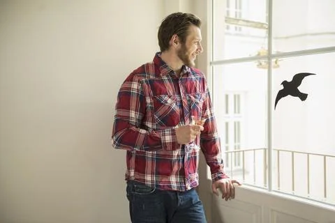 Man standing by window drinking white wine, Munich, Bavaria, Germany Stock Photos