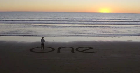 Man standing in the word one written on the beach Stock Footage 58649446