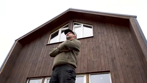A man stands against the backdrop of a house 4K Video stock 325988384
