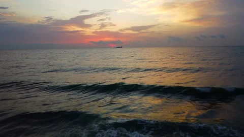 A man stands alone on a serene beach at sunrise, captured by drone. The peaceful Vídeos de archivo 283402548