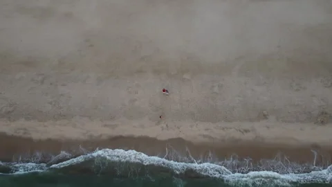 A man stands alone on a serene beach at sunrise, captured by drone. The peaceful Vídeos de archivo 283402695