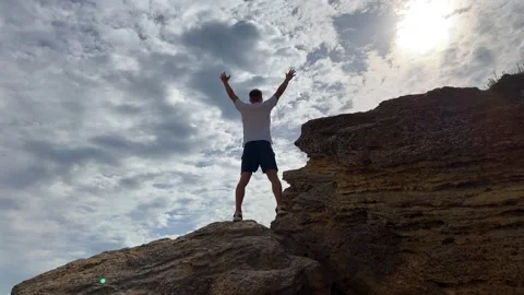 Man stands atop rugged rock. Concept of freedom and exploration 動画素材 340242002