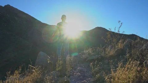 A man stands in awe on a mountain summit at sunset Stock Footage 324722784