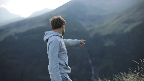 Man stands back on mountain top enjoying view pointing show finger slow motion Stock Footage 79974146
