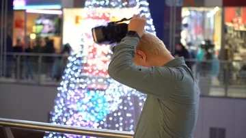 A man stands on a background of a Christmas tree in a shopping center with glass Stock Footage 86051146