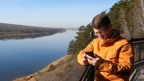 A man stands on the background of the river leaning on the railing. Stock Footage 118285842