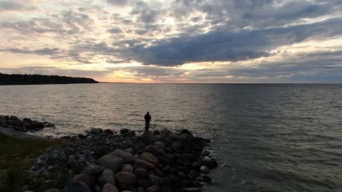 Man stands in the backlight by the sea. Sunset Stock Footage 115238455