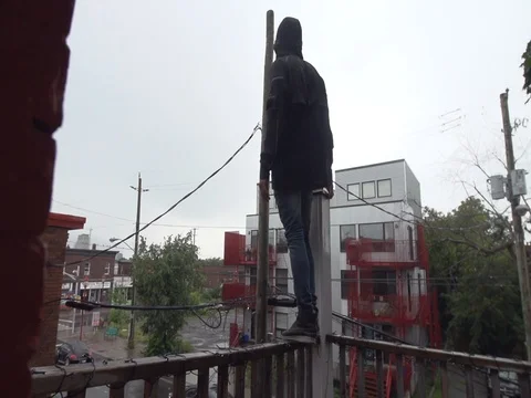 Man Stands on Balconey Looking Down at Streets Below Stock Footage 79736544