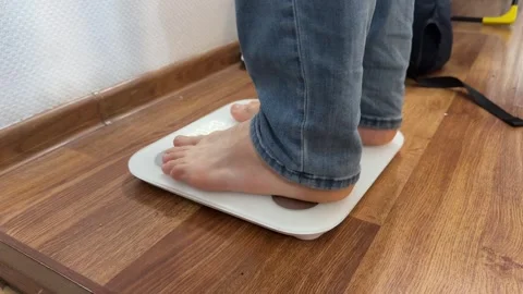A man stands barefoot on a digital bathroom scale Stock Footage 335073735