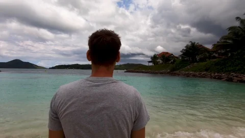 A man stands on the beach and looks at the bay in the ocean. Video stock 101632551