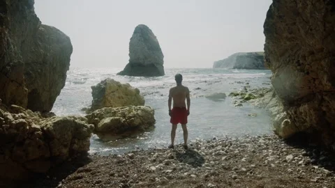 A man stands on a beach looking out at the ocean Stock Footage 297951195