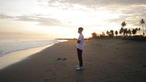Man stands in beach while sunrise comes Stock Footage 113862921