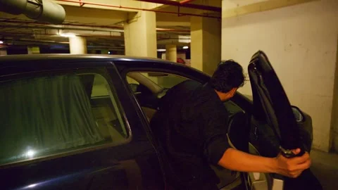 Man Stands Beside Car with Open Door in Basement Vídeos de archivo 305958511