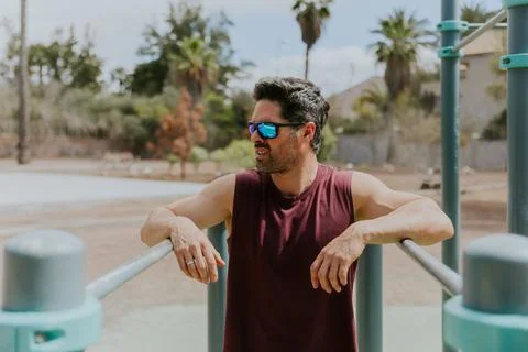 A man stands between bars at an outdoor gym while training, active lifestyl.. Stock Photos