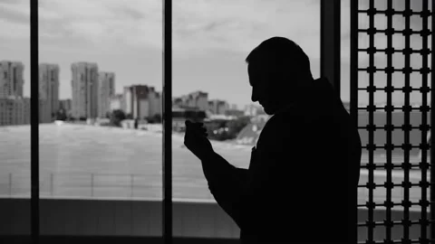 A man stands at a bright window and gets dressed for a meeting Stock Footage 201969188