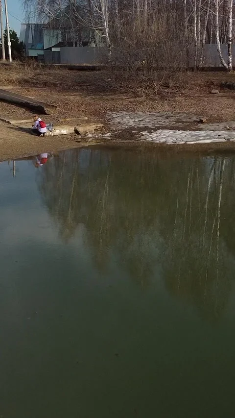 Man stands by calm water, casting a shadow Stockbeeldmateriaal 347499112
