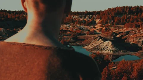 Man stands close-up on hill and looks at hilly valley similar to a Martian one. Stock Footage 160220557