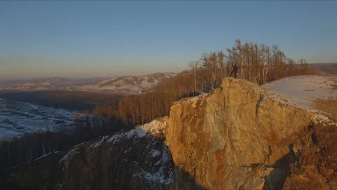 A man stands on the edge of a cliff and enjoys the sunset. Stock Footage 87919361