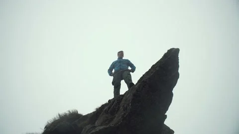 A man stands on the edge of a cliff, the rise of a peak, fog, silhouette Stock Footage 218438951
