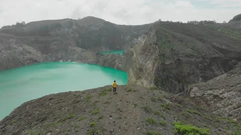 A man stands on the edge of the Kelimutu volcanic crater Video stock 265829882