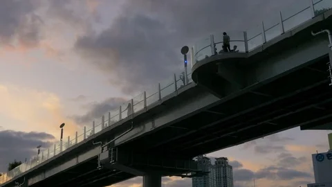 A man stands on an elevated bridge. It is a low angle view of the sky at sunset. Stock Footage 85418190