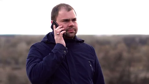 A man stands in a field and talking on the phone. Stock Footage 127447050