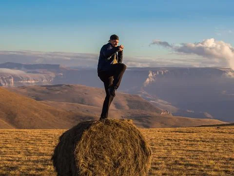 A man stands in a fighting pose on one leg on a haystack in an autumn field Stock Photos