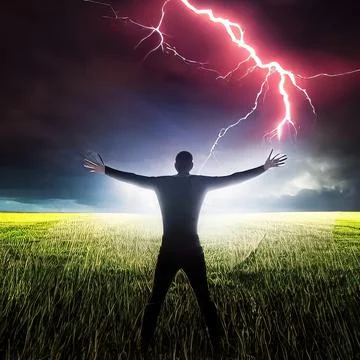 A man stands in a flash of lightning with his hands raised to the sky. Field  스톡 사진