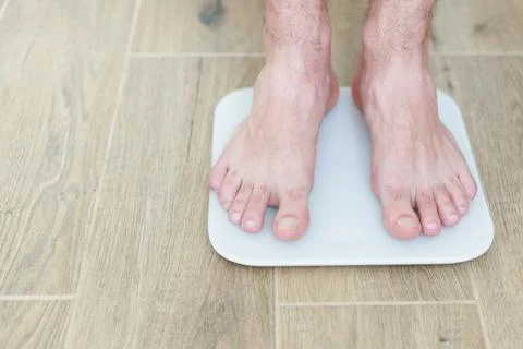 A man stands on a floor scale on the floor close-up Foto stock