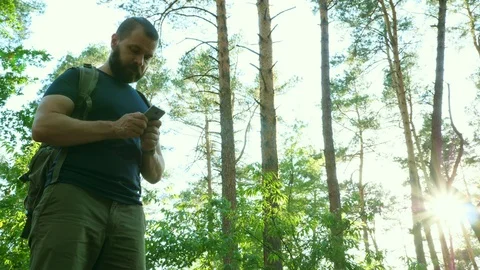 Man stands in forest and communicates with short messages on his smartphone. Stock Footage 90593301
