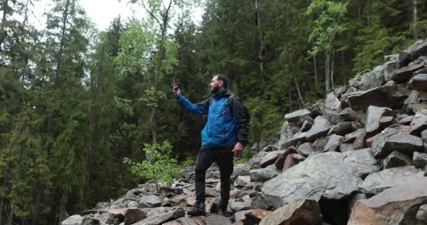 A man stands in the forest on large stones and takes out a smartphone Stock-Footage 243599024