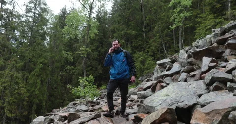 A man stands in the forest on large stones and takes out a smartphone Stock-Footage 243599358