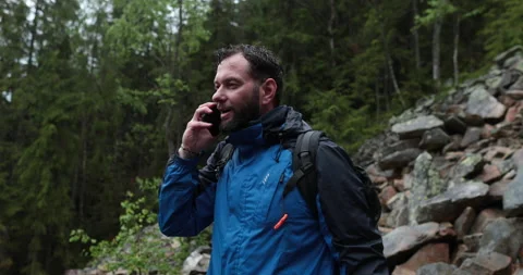 A man stands in the forest on large stones and takes out a smartphone Stock Footage 243600720