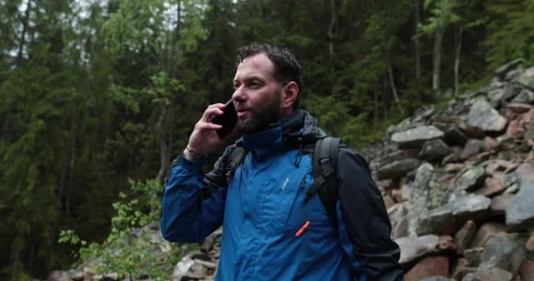 A man stands in the forest on large stones and takes out a smartphone Stock Footage 243600914