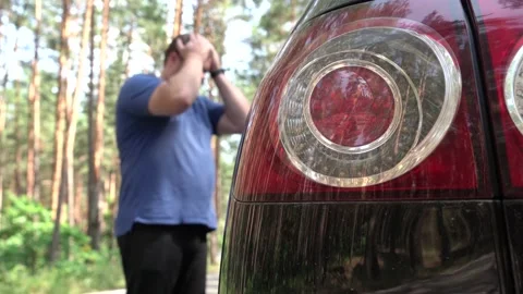 The man stands in a front of black car and takes up his head in frustration. The Stock Footage 157213148