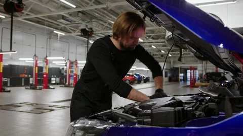 A man stands in front of the open hood and unscrews the lid with a wrench Stock Footage 221546856