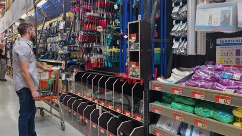 A man stands in front of a tool shelf in a hardware store, thinking and 動画素材 312369536