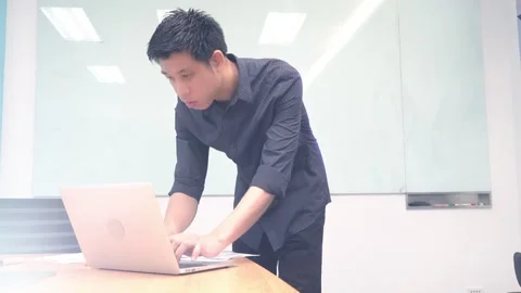 A man stands in front of a white board with a laptop on a table behind him Stock Footage 314899358
