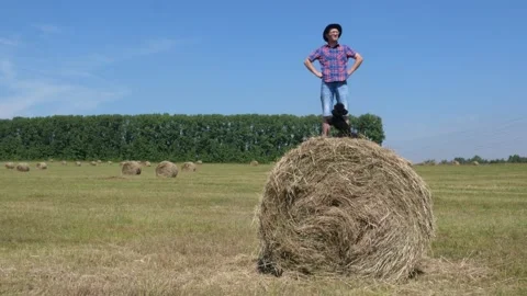 A man stands on a haystack with a dog. Stock Footage 135458394