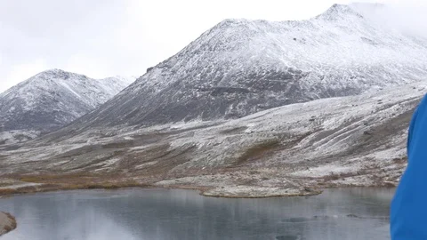 A man stands on a high point in the mountains and admires a beautiful view Stock Footage 96476754