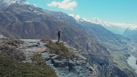 Man stands on high rock at edge of abyss, awesome sunny mountain panorama around Stock Footage 126722489