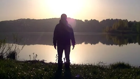 The man stands with his arms spread wide and looks at the rising sun Stock Footage 130221342