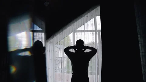 The man stands with his back to the camera in front of the window Stock Footage 250483994