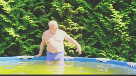 Man stands in inflatable pool with warm water and waves hand Stock Footage 139795488